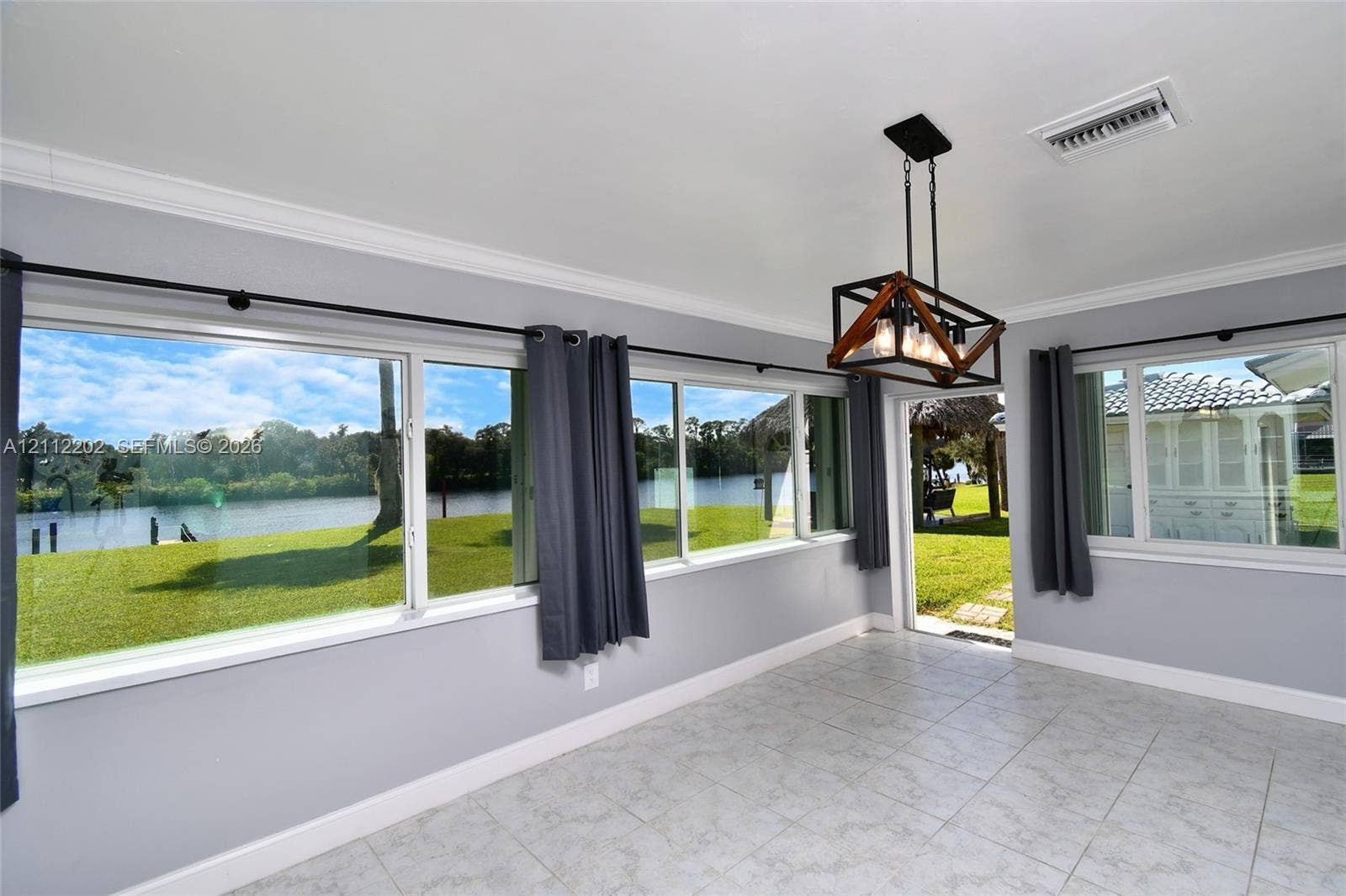 3233 Shell Lane, Labelle, FL 33935 Light-filled room featuring large windows, tile flooring, crown molding, and a geometric-frame pendant light