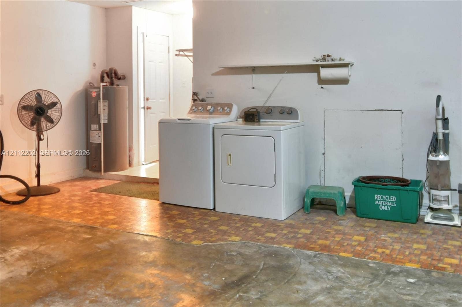 3233 Shell Lane, Labelle, FL 33935 Utility area featuring a tiled floor, wall-mounted storage shelf, and dedicated water heater