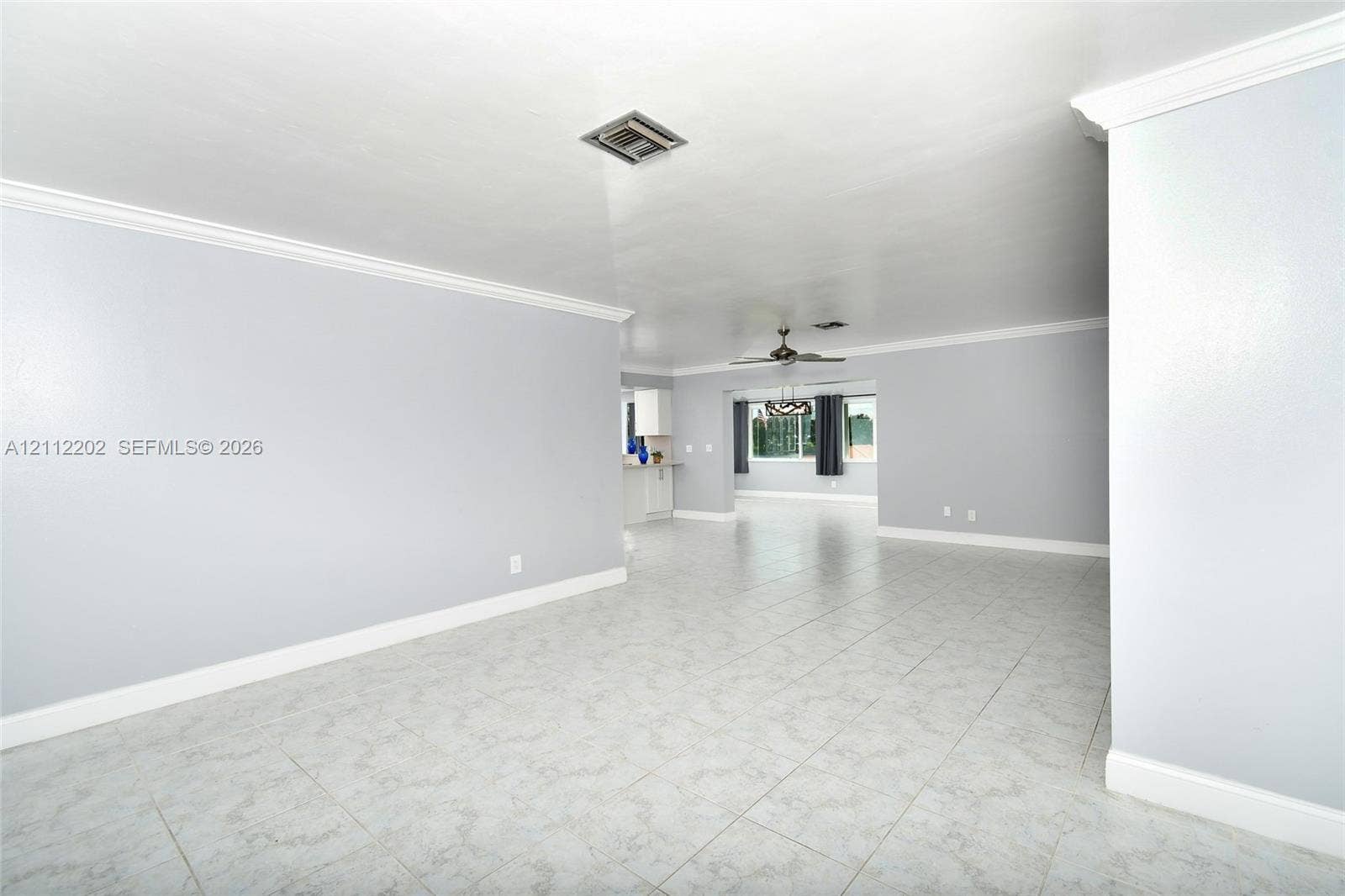 3233 Shell Lane, Labelle, FL 33935 Open-concept interior featuring neutral wall tones, large-format tile flooring, crown molding, and a ceiling fan