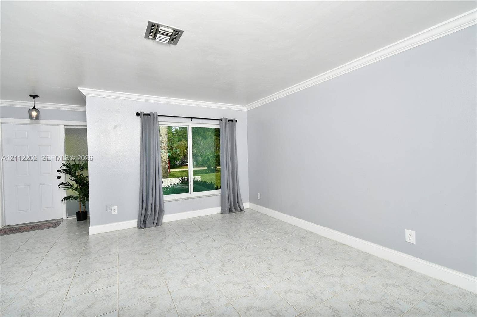 3233 Shell Lane, Labelle, FL 33935 Living area featuring light-toned tile flooring, neutral wall paint, multi-pane window, crown molding, and a paneled entry door