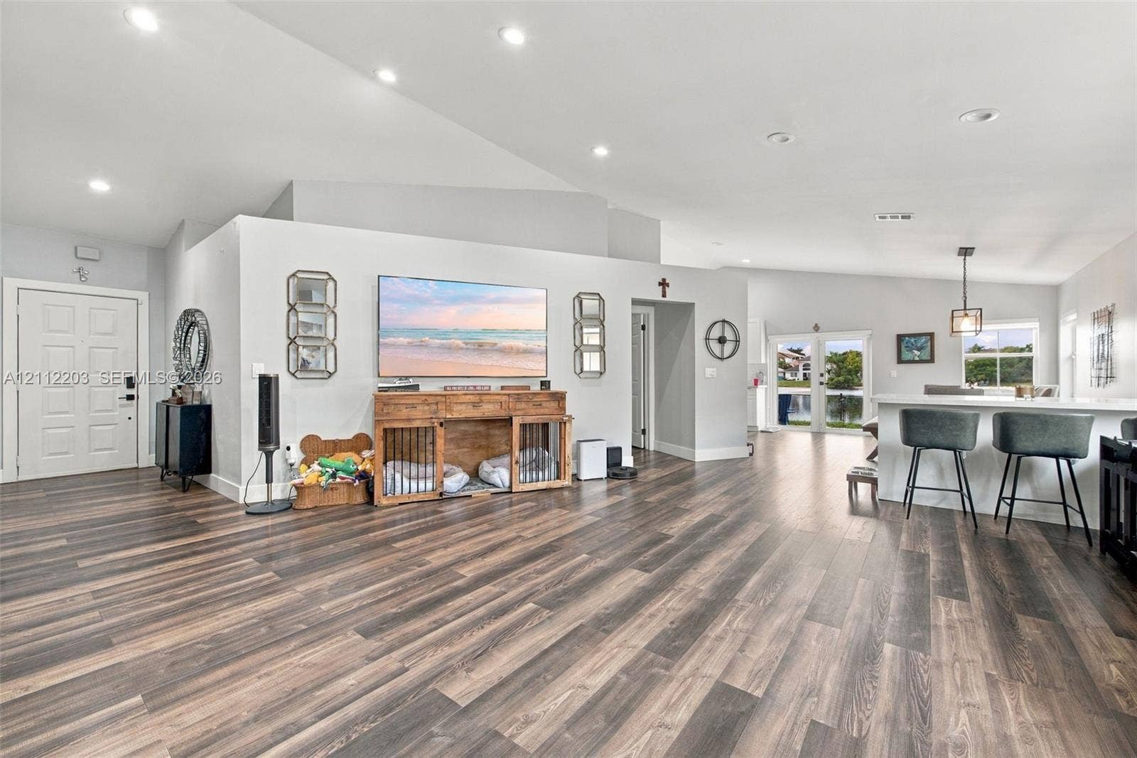 Open-concept interior featuring vaulted ceilings, wood-finish flooring, recessed lighting, and glass-paneled double doors