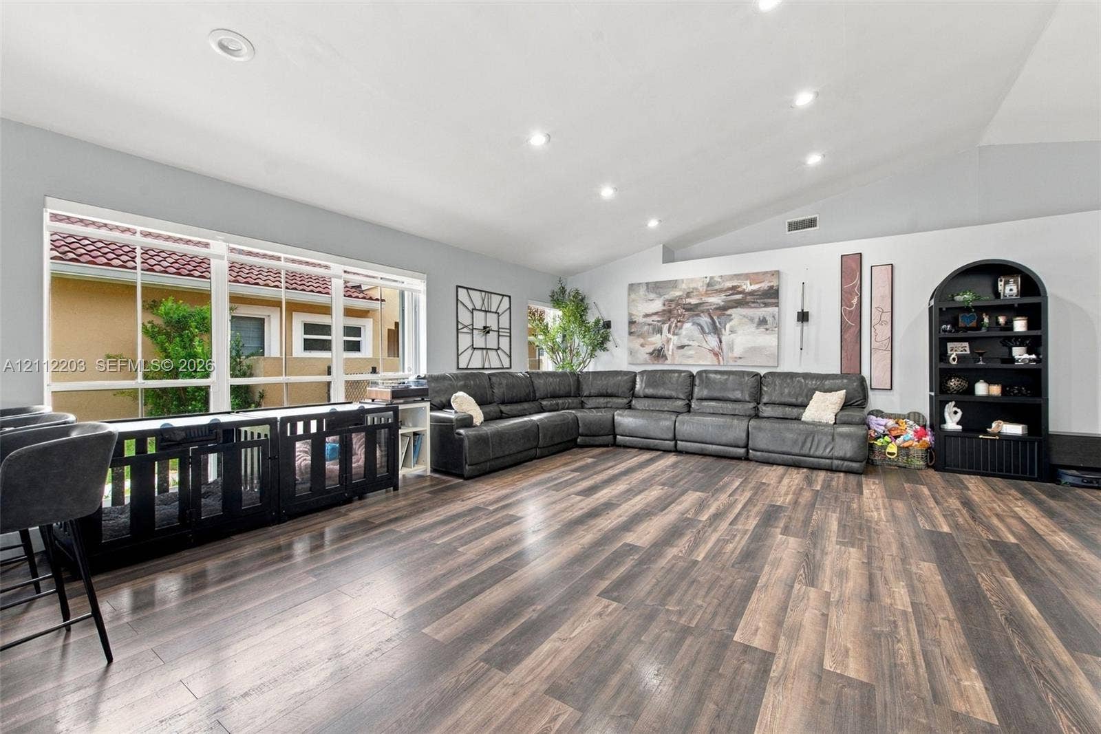 Spacious interior featuring a vaulted ceiling, wood-finish flooring, recessed lighting, and a large multi-pane window