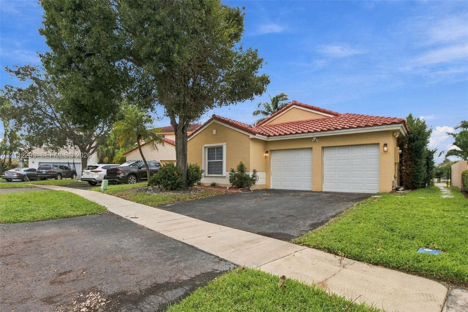 Stucco exterior featuring a dual-car garage and a pitched red-tile roof