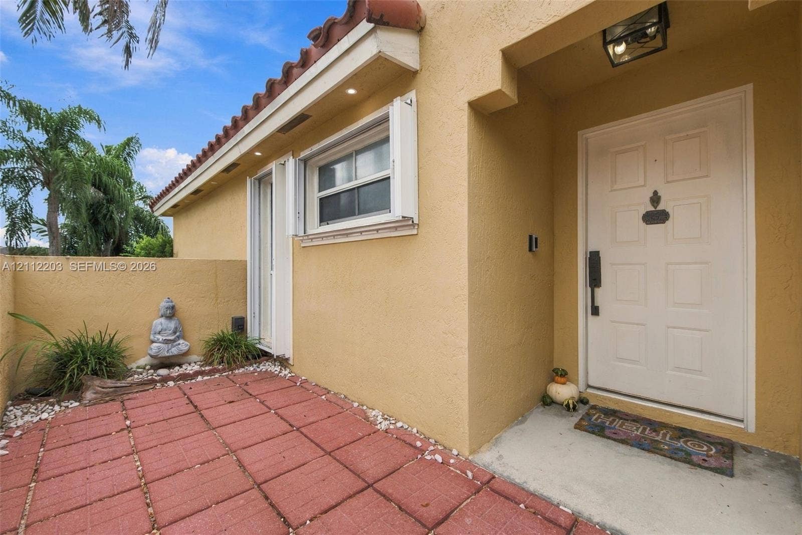 Stucco exterior entryway featuring a terracotta-tiled patio, recessed soffit lighting, and a white paneled front door