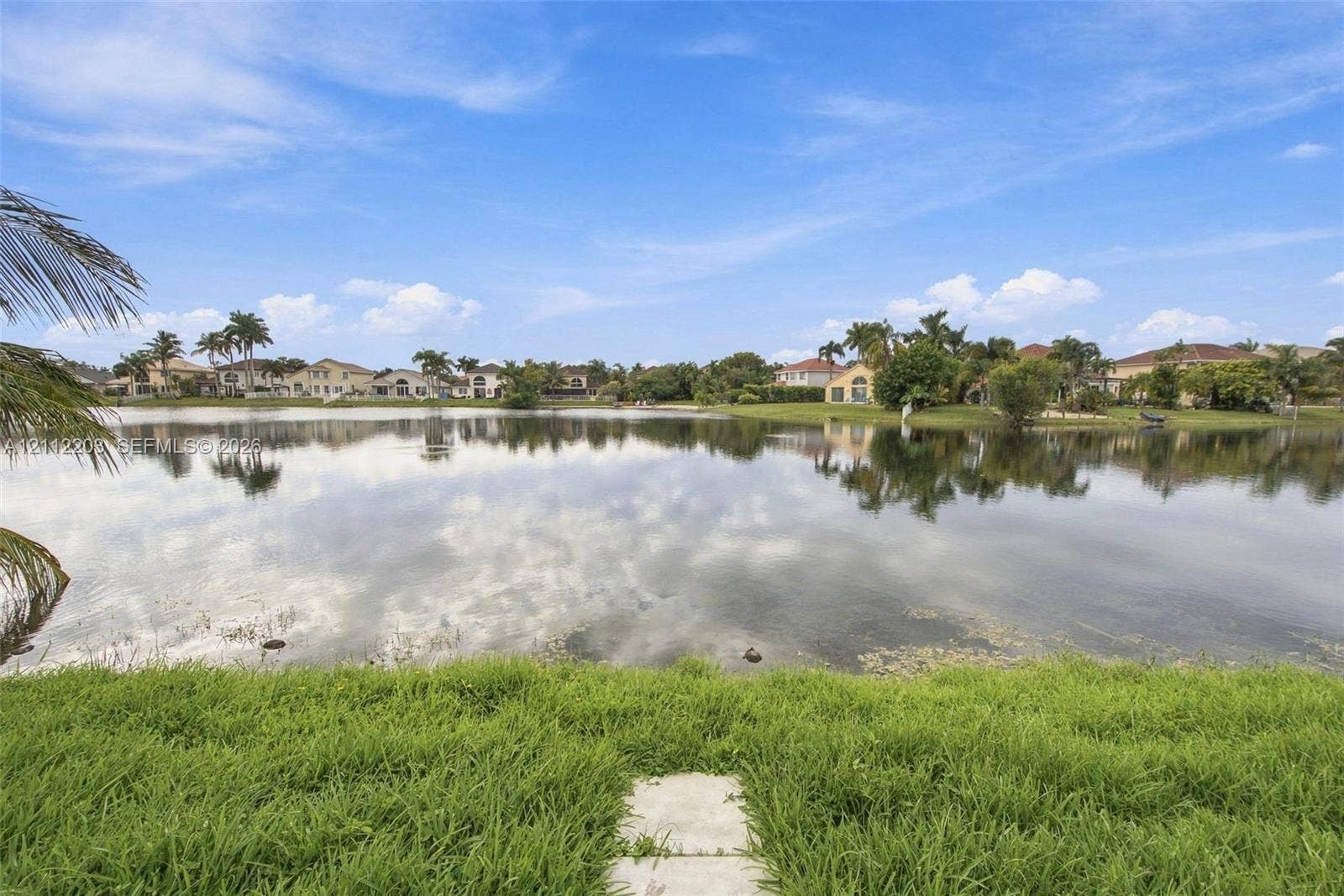 Waterfront lot featuring a manicured lawn and stone-paved walkway