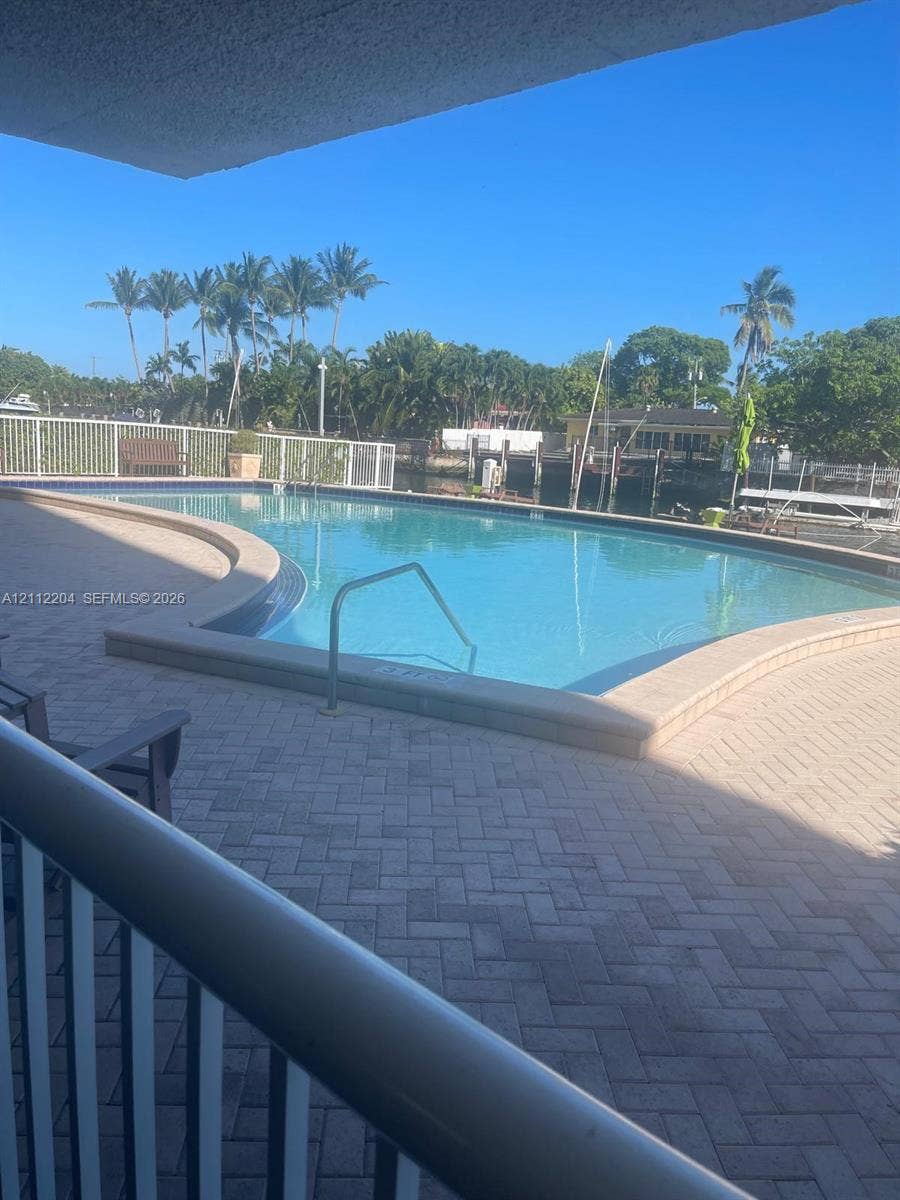 2020 NE 135th Street, #910, North Miami, North Miami, FL 33181 Swimming pool featuring a herringbone-patterned paver deck, metal safety railing, and integrated water access steps