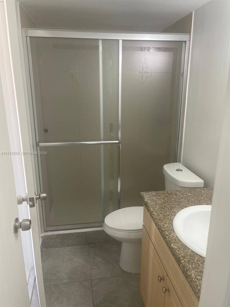 2020 NE 135th Street, #910, North Miami, North Miami, FL 33181 Bathroom featuring a shower stall with a sliding glass door, vanity with a stone-finish countertop, and integrated sink