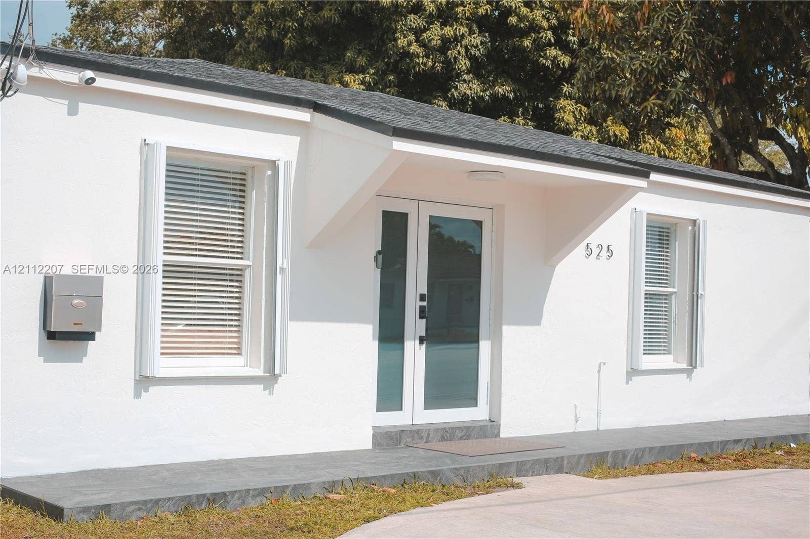 525 SW 67th Avenue, Miami, Miami, FL 33144 Exterior featuring smooth white stucco finish, dual-glass entry doors, dark stone-tile porch, and windows with white shutter accents