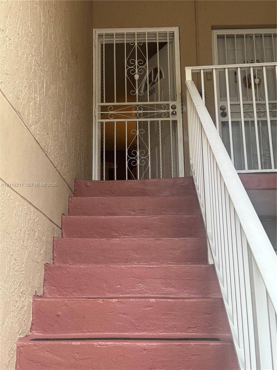 Stucco exterior staircase with painted concrete steps and metal railing featuring decorative security gates