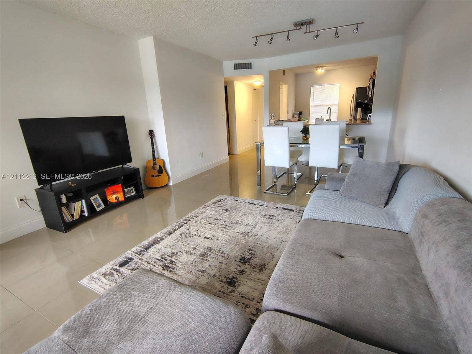 2900 NW 42nd Avenue, #304A, Coconut Creek, Coconut Creek, FL 33066 Open-concept interior featuring large-format tile flooring, recessed track lighting, and a kitchen pass-through window with an integrated breakfast bar