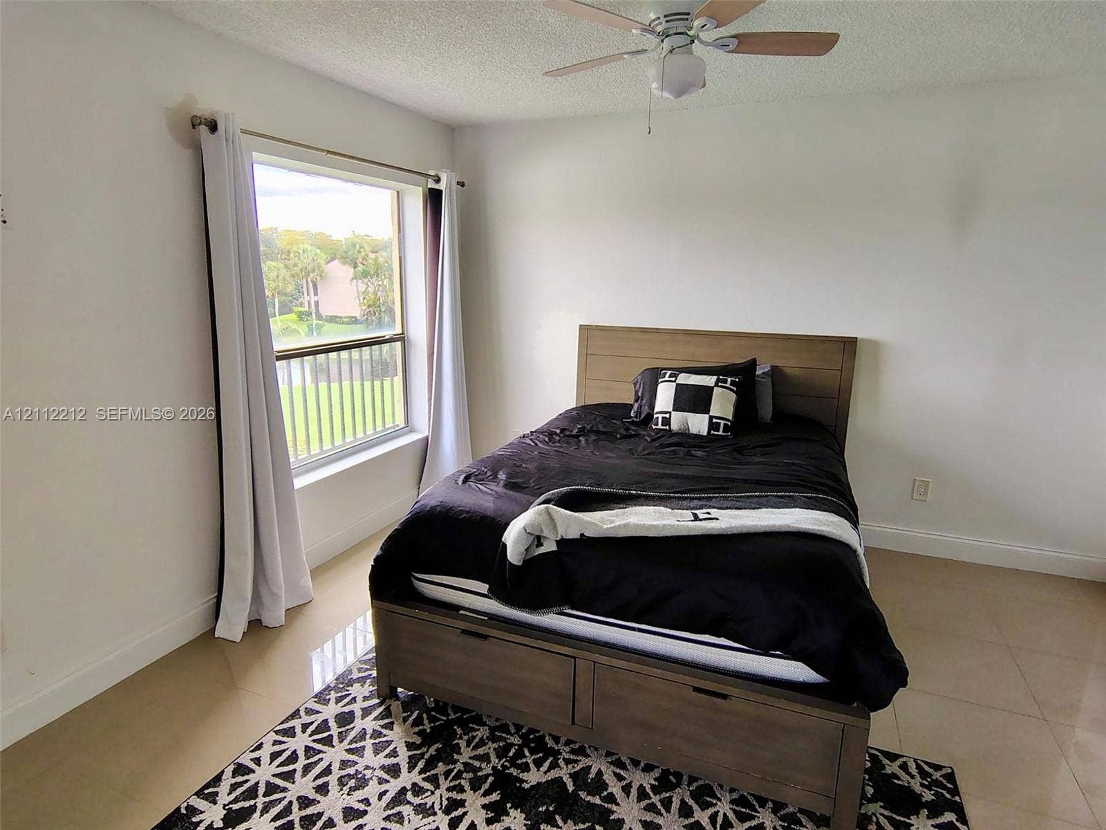 2900 NW 42nd Avenue, #304A, Coconut Creek, Coconut Creek, FL 33066 Neutral interior space featuring polished tile flooring, a textured ceiling, a ceiling fan with light fixture, and a large window with outdoor greenery exposure