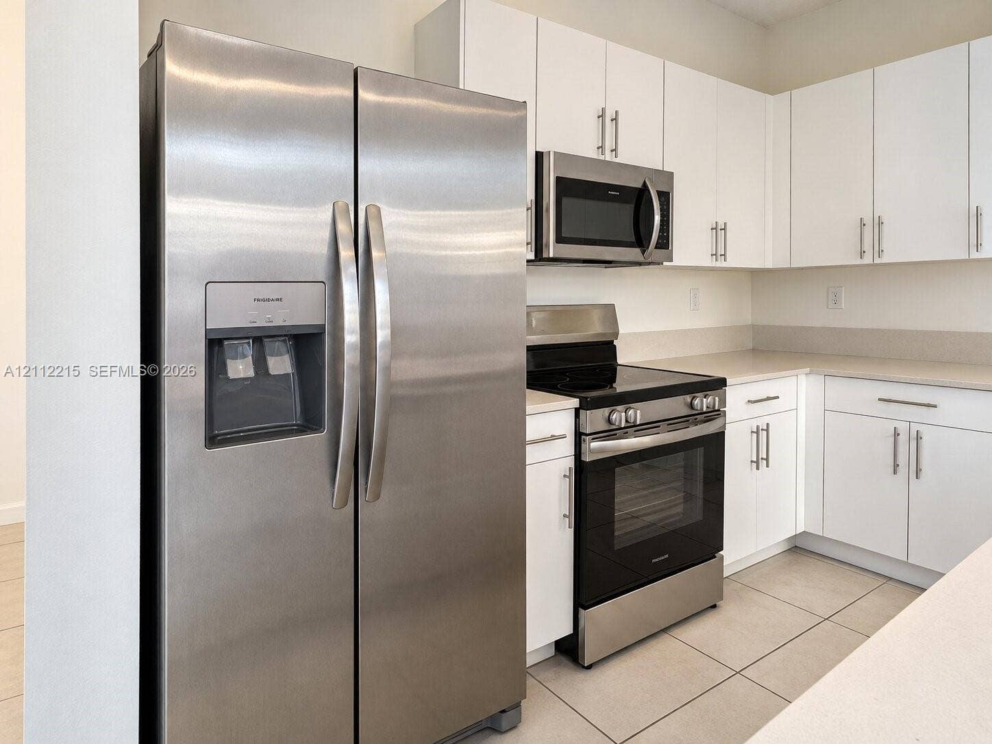 1161 SE 1 Street, #0, Florida City, Florida City, FL 33034 Kitchen featuring white cabinetry with brushed metal hardware, stainless steel side-by-side refrigerator, matching microwave, black range, and tile flooring