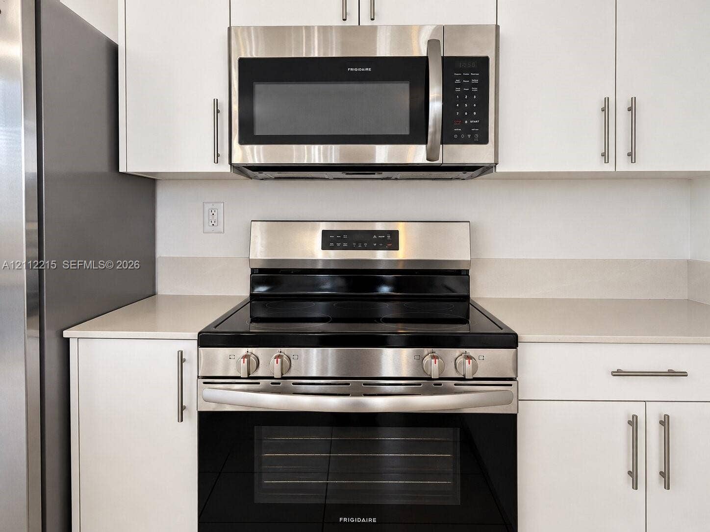 1161 SE 1 Street, #0, Florida City, Florida City, FL 33034 Stainless steel electric range and matching over-the-range microwave, crisp white cabinetry with modern pulls, and light-toned solid surface countertops