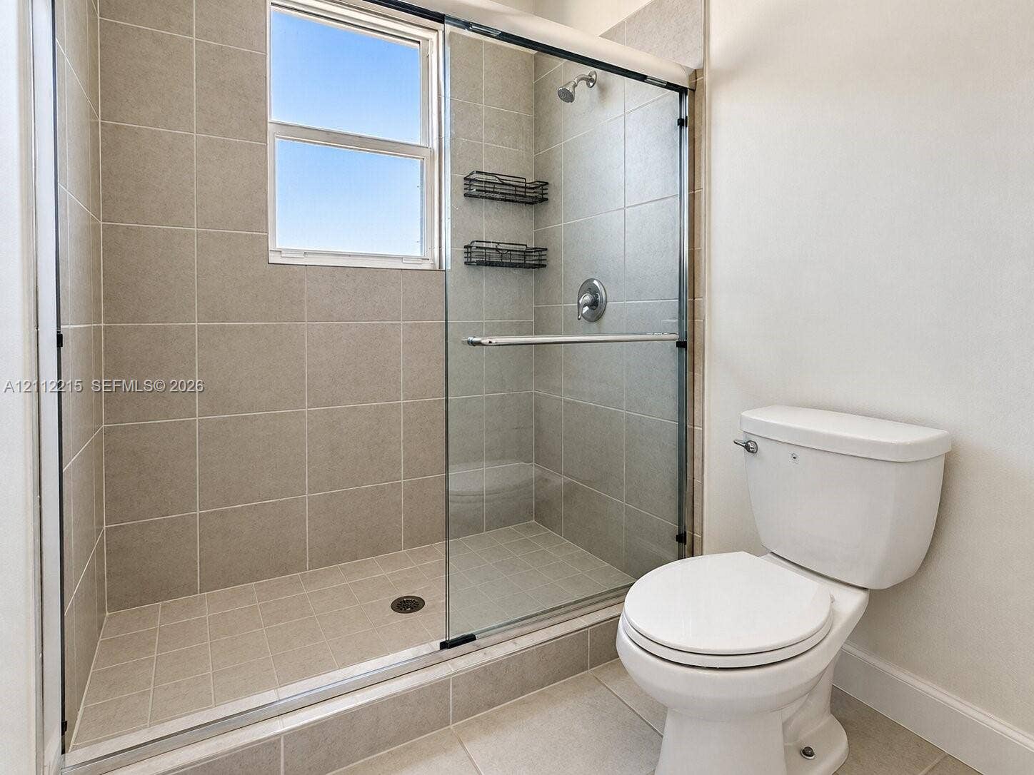 1161 SE 1 Street, #0, Florida City, Florida City, FL 33034 Walk-in shower enclosure featuring floor-to-ceiling tile, a sliding glass door, a window, and a wall-mounted showerhead
