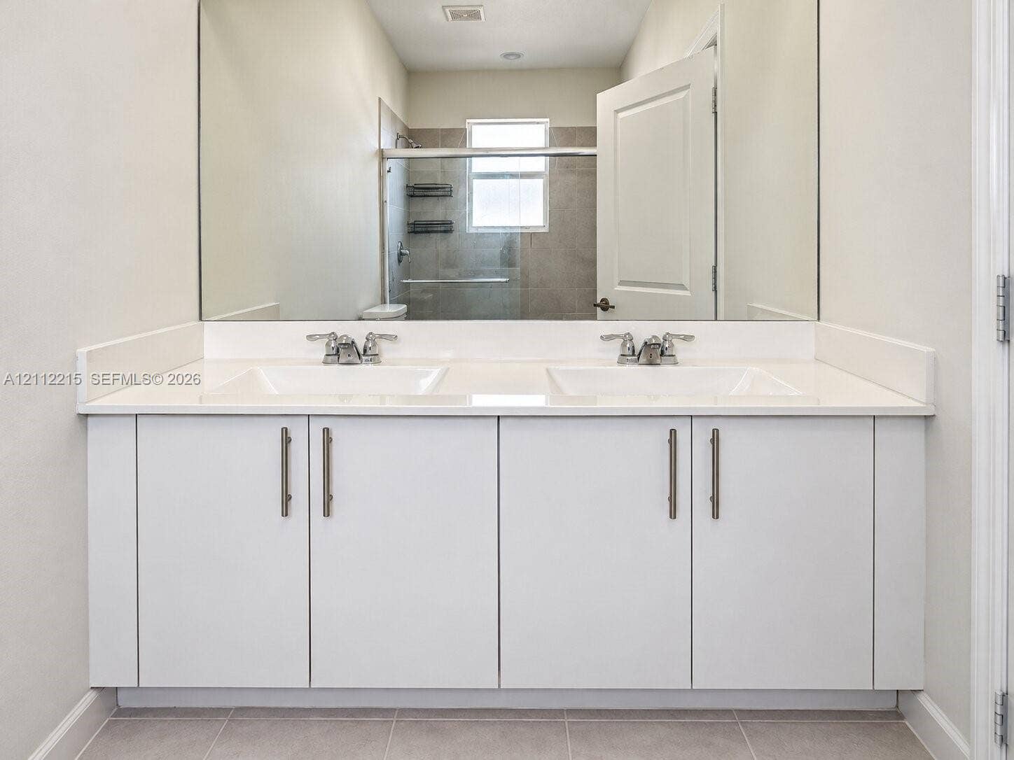 1161 SE 1 Street, #0, Florida City, Florida City, FL 33034 Dual-sink vanity featuring a solid surface countertop, white cabinetry with metallic hardware, and a full-width wall mirror