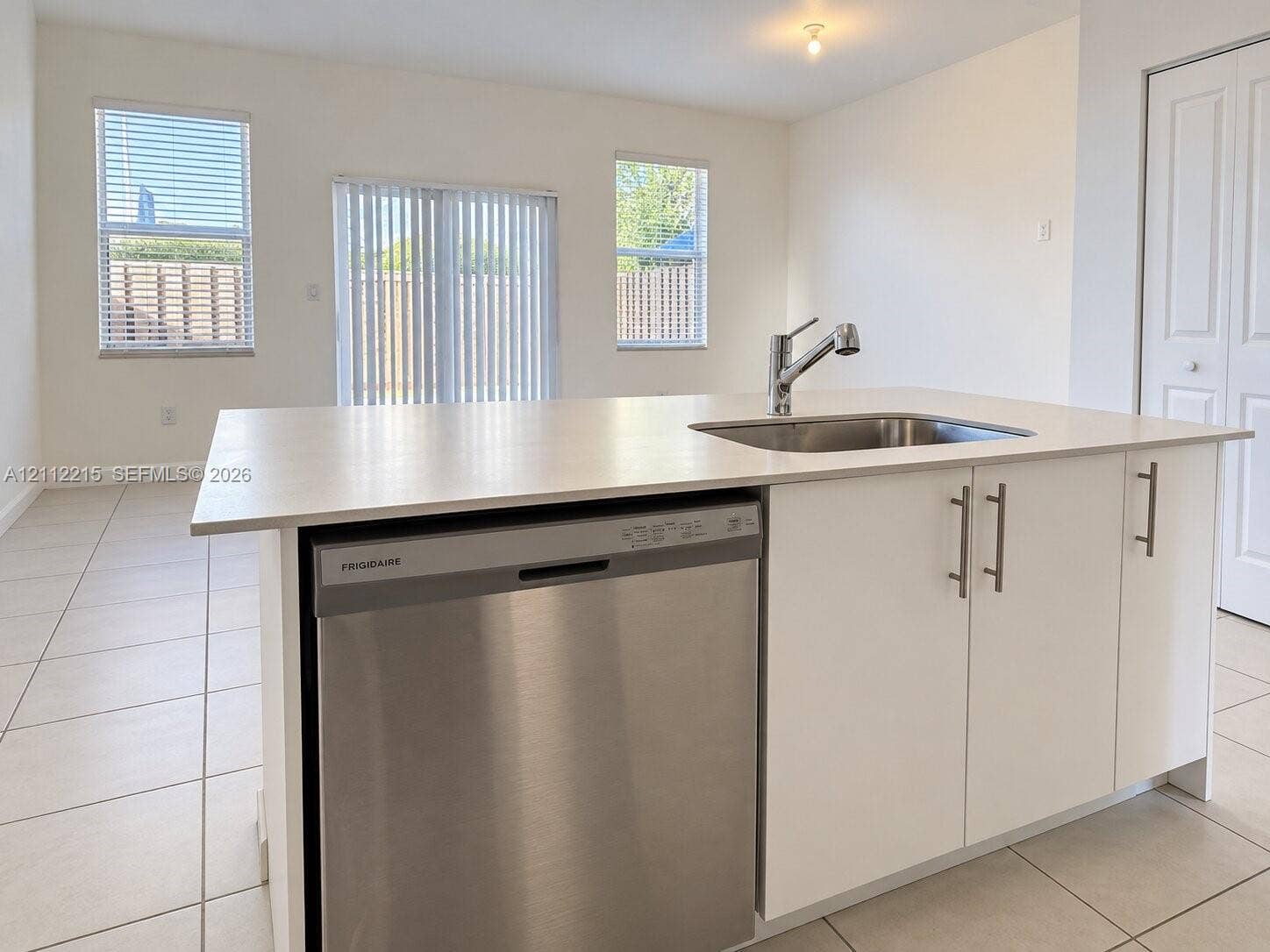1161 SE 1 Street, #0, Florida City, Florida City, FL 33034 Kitchen island featuring a stainless steel dishwasher, an undermount sink with a high-arch faucet, white cabinetry, and light-toned countertops