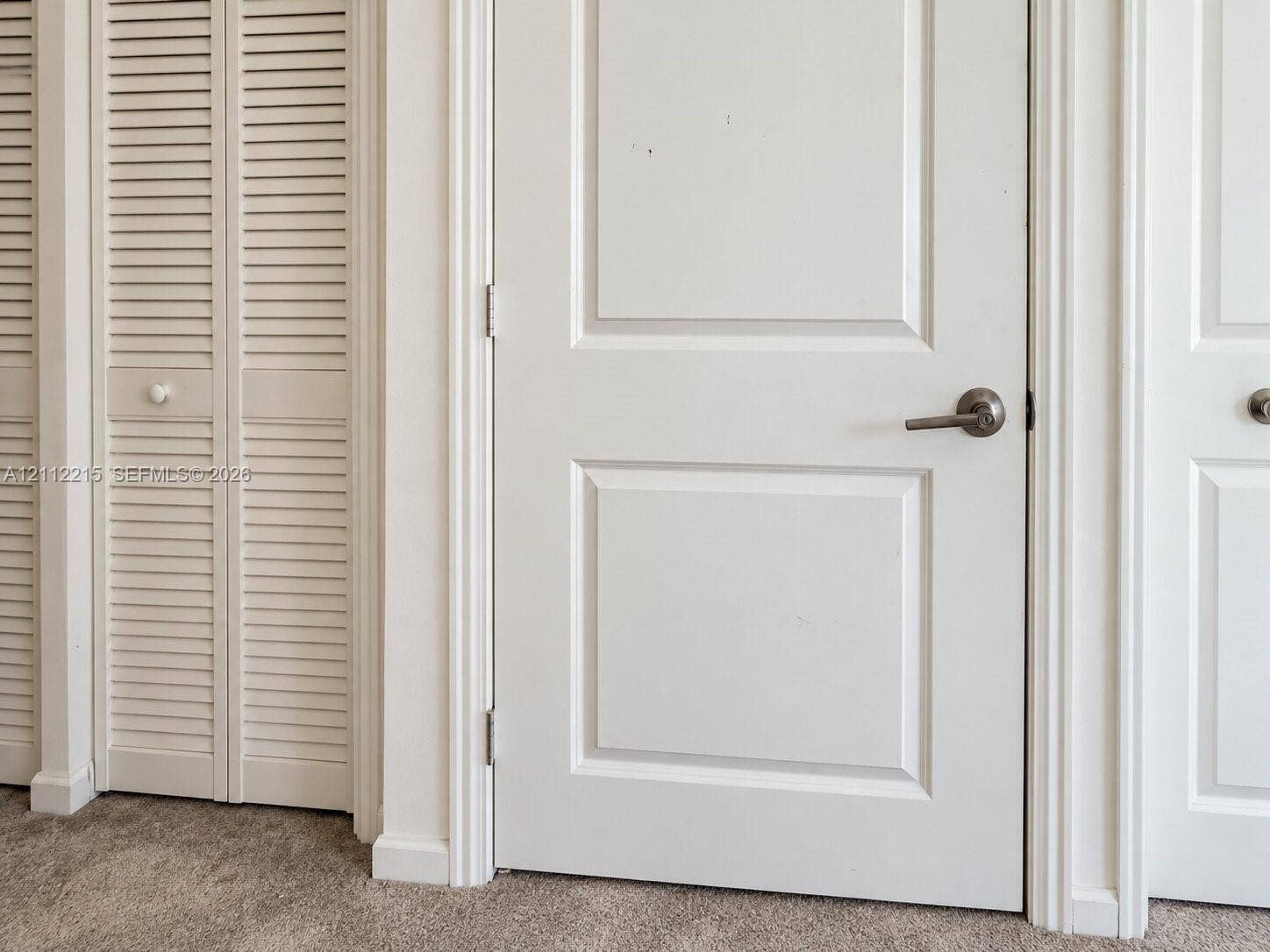 1161 SE 1 Street, #0, Florida City, Florida City, FL 33034 Interior featuring white two-panel solid core doors, white louvered bifold closet doors, and brushed nickel lever-style door hardware