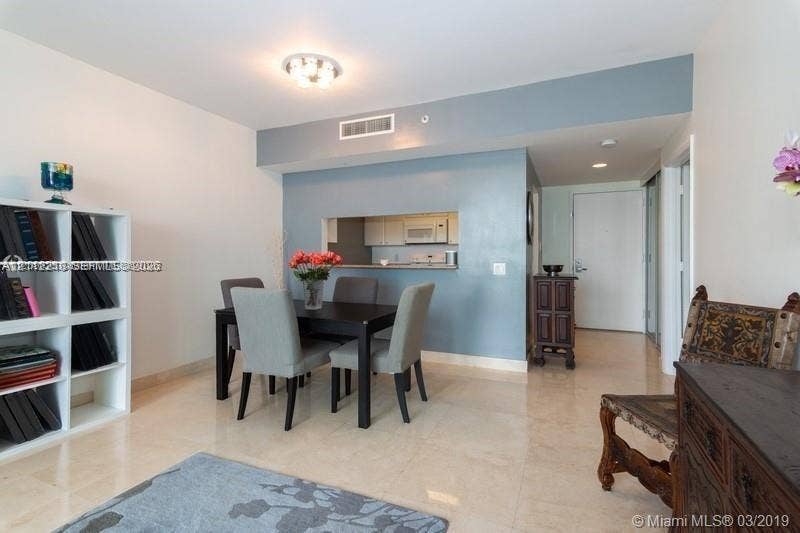 2475 Brickell Avenue, #1905, Miami, Miami, FL 33129 Neutral-toned stone flooring, built-in white shelving unit, and a kitchen pass-through window with an integrated counter