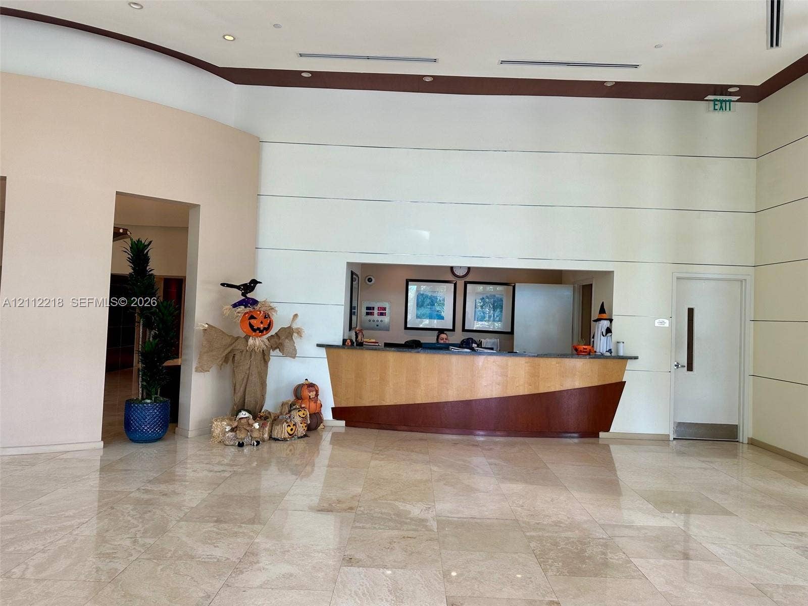2475 Brickell Avenue, #1905, Miami, Miami, FL 33129 Grand lobby featuring high ceilings, polished stone flooring, recessed lighting, and a built-in reception desk with tiered wood-finish detailing