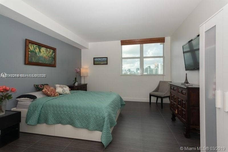 2475 Brickell Avenue, #1905, Miami, Miami, FL 33129 Bedroom featuring dark tile flooring, a neutral color palette, an accent wall, and a large window