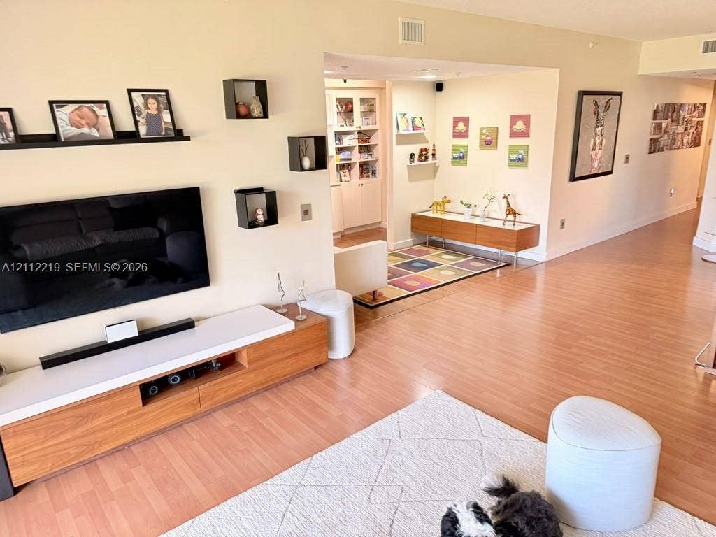 Wood-finish flooring throughout, wall-mounted display shelving, and built-in cabinetry featuring glass-panel doors