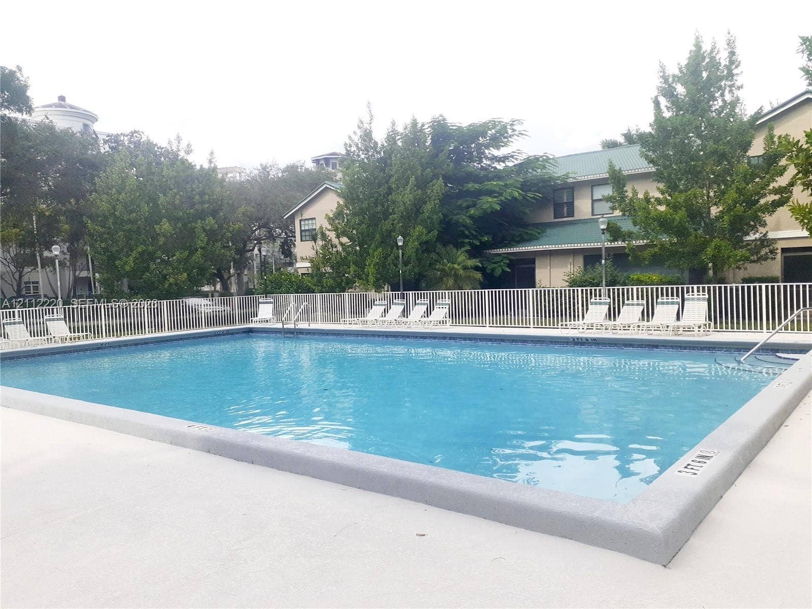 508 W Westree Lane, #508, Plantation, Plantation, FL 33324 Rectangular swimming pool featuring a concrete deck, white perimeter fencing, metal ladder access, and integrated depth markers