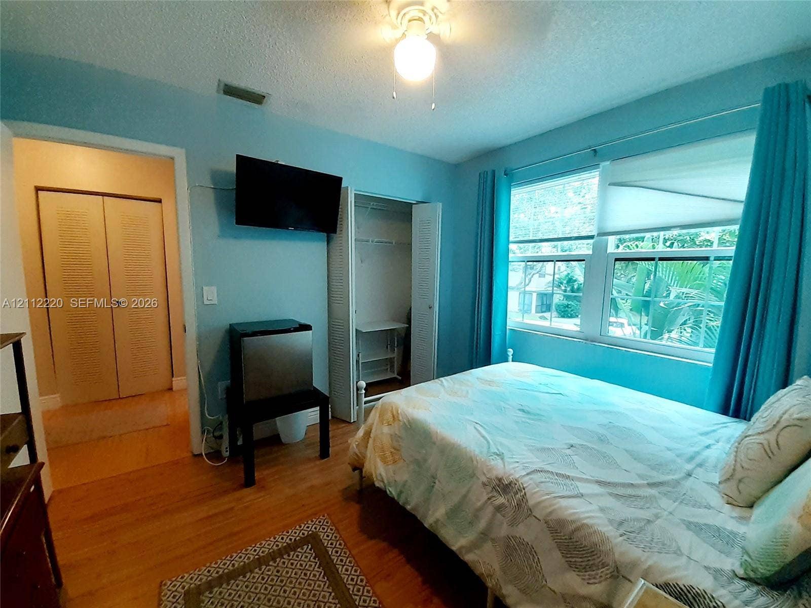 508 W Westree Lane, #508, Plantation, Plantation, FL 33324 Room featuring wood-finish flooring, dual bi-fold closet doors, a multi-pane window, and a ceiling-mounted light fixture