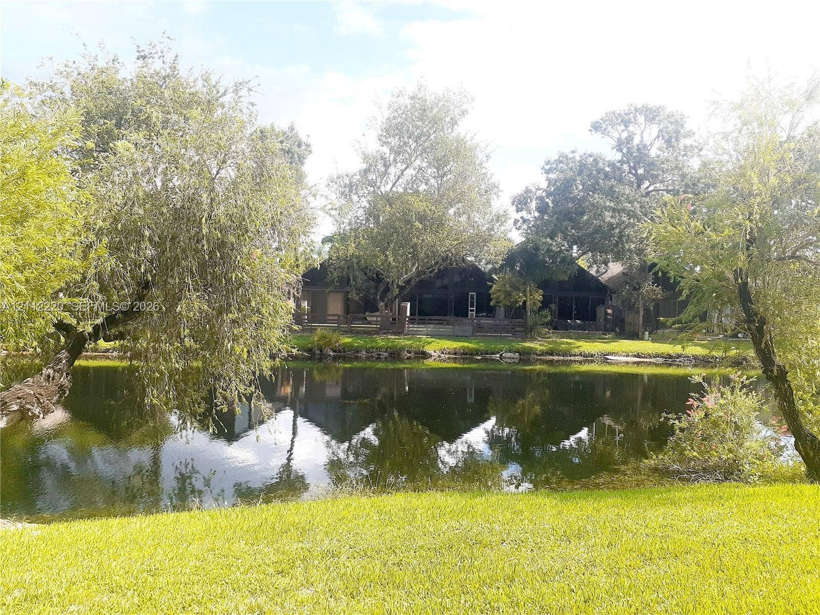 508 W Westree Lane, #508, Plantation, Plantation, FL 33324 Waterfront property featuring a manicured lawn, mature trees, and a screened-in porch