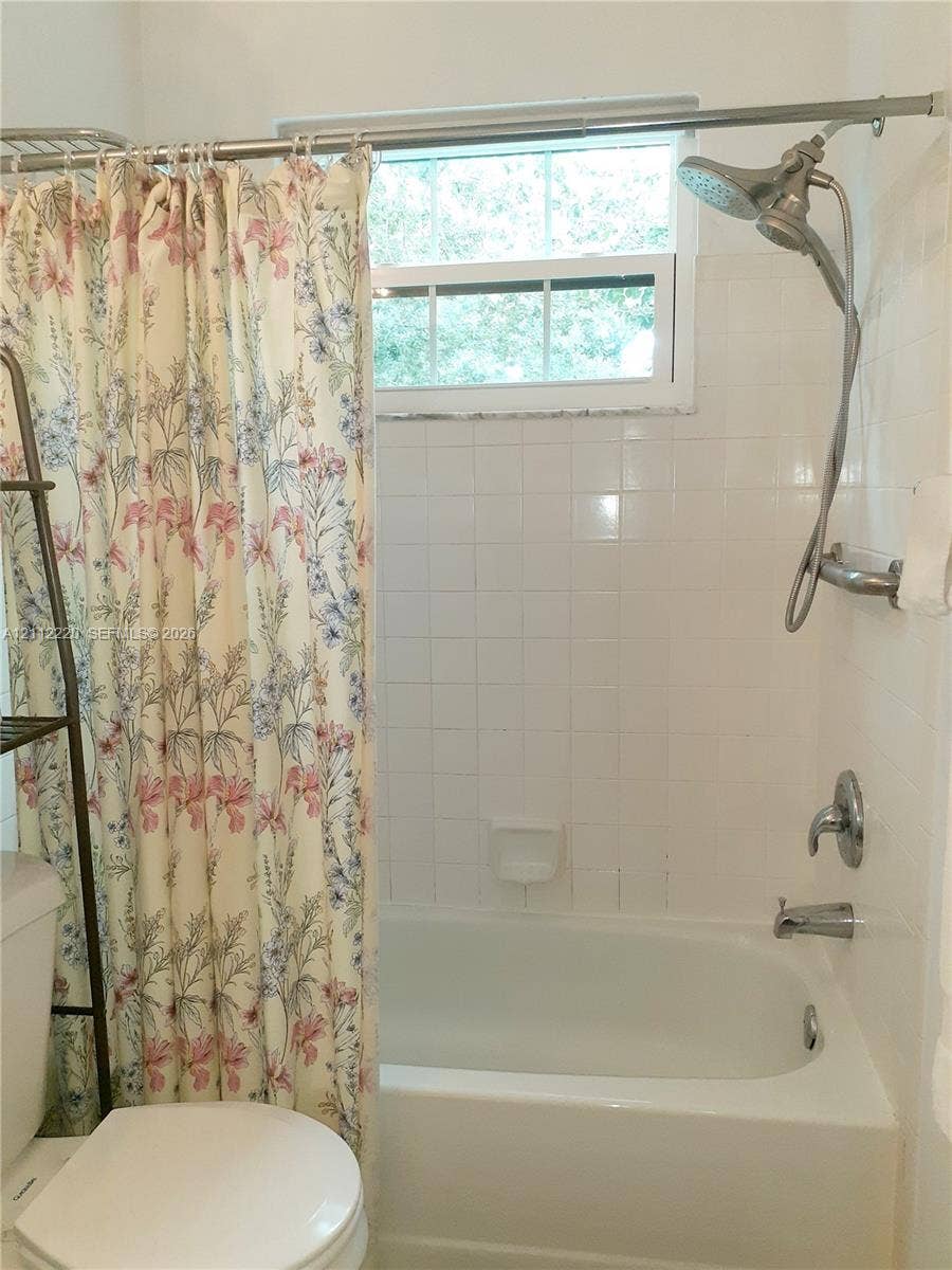 508 W Westree Lane, #508, Plantation, Plantation, FL 33324 Bathtub and shower combination featuring white tiled wall surround, stainless steel dual shower head fixture, and built-in recessed soap dish