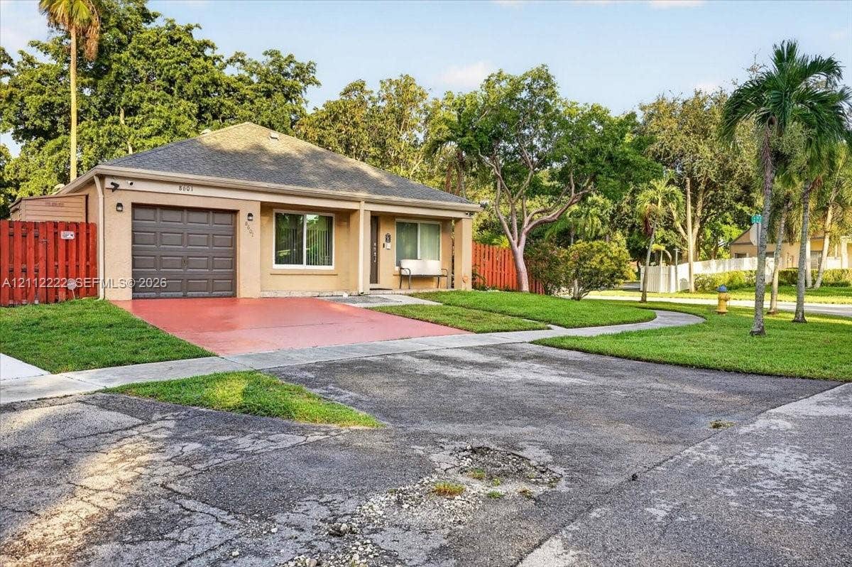 Single-story residence featuring a tan stucco exterior, a dark-toned shingle roof, an integrated single-car garage, and a concrete driveway
