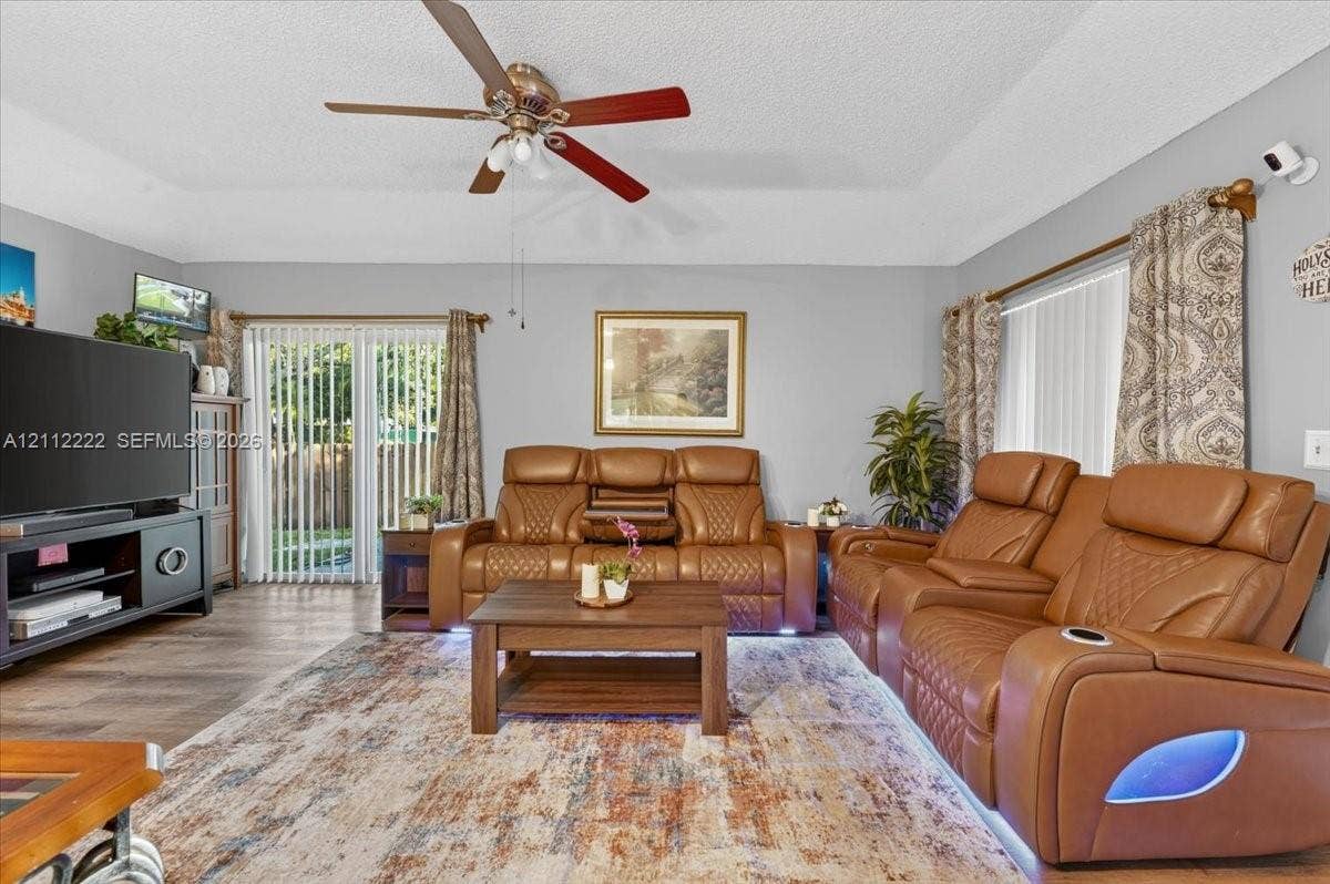 Living area featuring tray ceilings, wood-finish flooring, and a ceiling fan