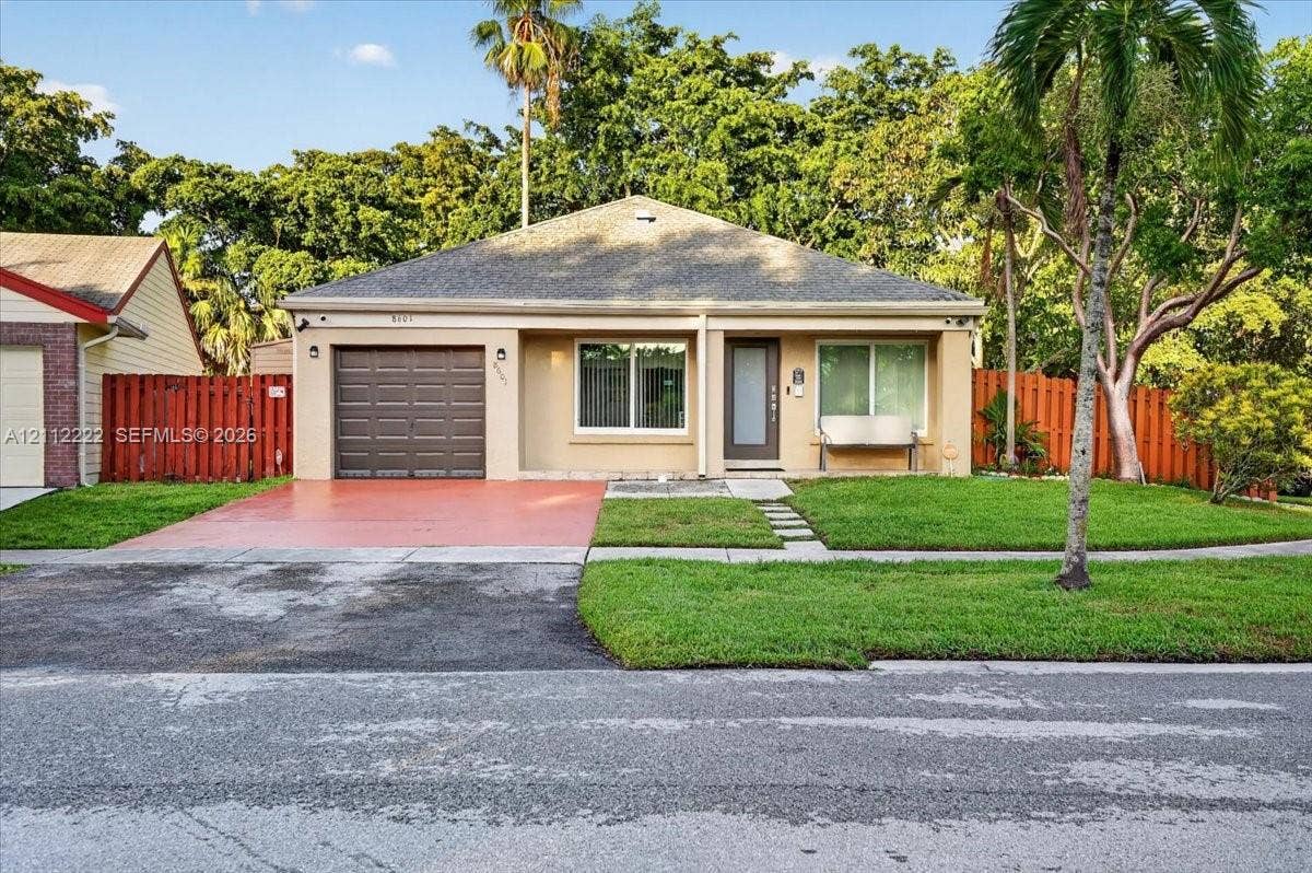 Single-story exterior featuring a hip roof, integrated garage, concrete driveway, and front lawn with mature palm trees