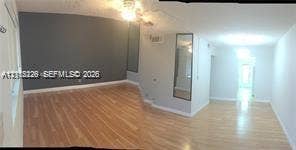 1450 NE 170th Street, #210, North Miami Beach, North Miami Beach, FL 33162 Interior space featuring wood-finish flooring, a dark-toned accent wall, and a full-length wall-mounted mirror