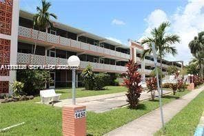 1450 NE 170th Street, #210, North Miami Beach, North Miami Beach, FL 33162 Multi-story exterior featuring decorative concrete latticework, covered balconies, brick-accented pillars, and landscaped grounds with mature palm trees