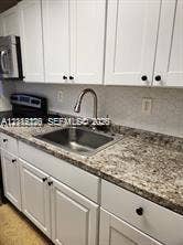 1450 NE 170th Street, #210, North Miami Beach, North Miami Beach, FL 33162 Kitchen featuring white shaker-style cabinetry, stone-finish countertops, stainless steel undermount sink, gooseneck faucet, and built-in appliances