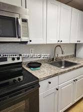 1450 NE 170th Street, #210, North Miami Beach, North Miami Beach, FL 33162 Kitchen featuring white shaker-style cabinetry, stone-patterned laminate countertops, a stainless steel undermount sink with a gooseneck faucet, and stainless steel built-in appliances