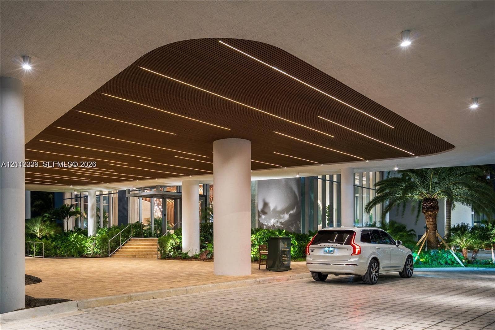 725 NE 24th Street, #706, Miami, Miami, FL 33137 Covered porte-cochre featuring a linear wood-slat ceiling, integrated LED recessed lighting, structural support columns, and paved motor court