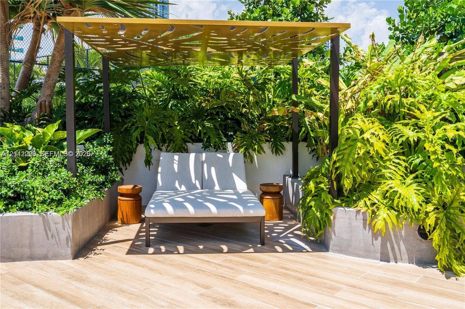 725 NE 24th Street, #706, Miami, Miami, FL 33137 Outdoor terrace featuring wood-finish tile flooring, a custom metal pergola with laser-cut decorative detailing, and integrated concrete planters with mature landscaping