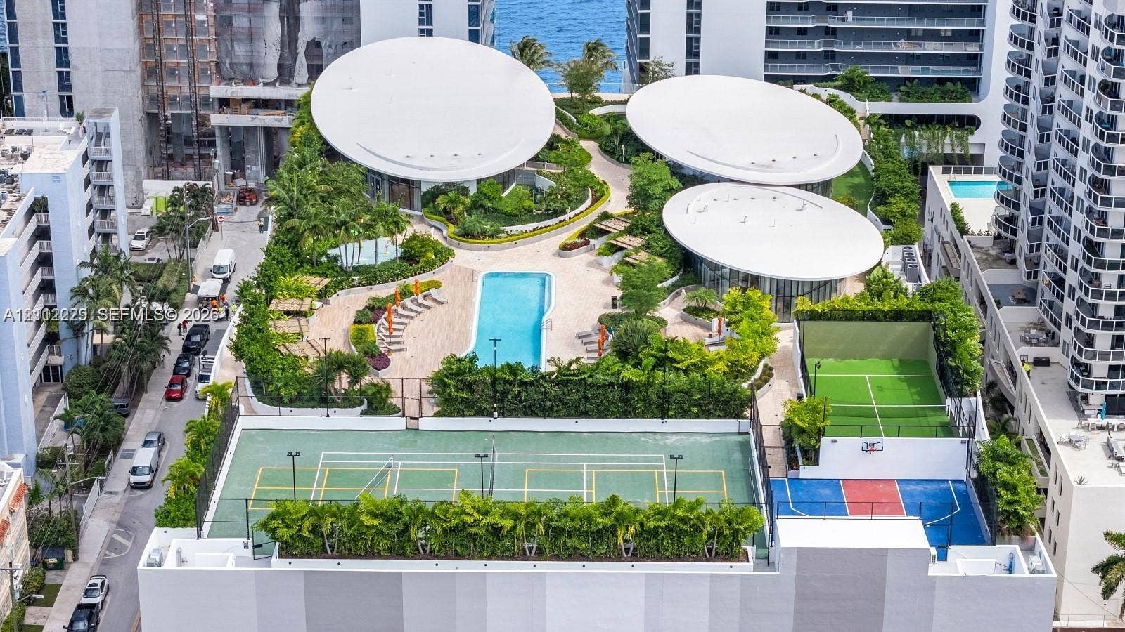 725 NE 24th Street, #706, Miami, Miami, FL 33137 Elevated amenity deck featuring a swimming pool, tennis court, multi-sport court, landscaped green spaces, and distinctive modern architectural structures