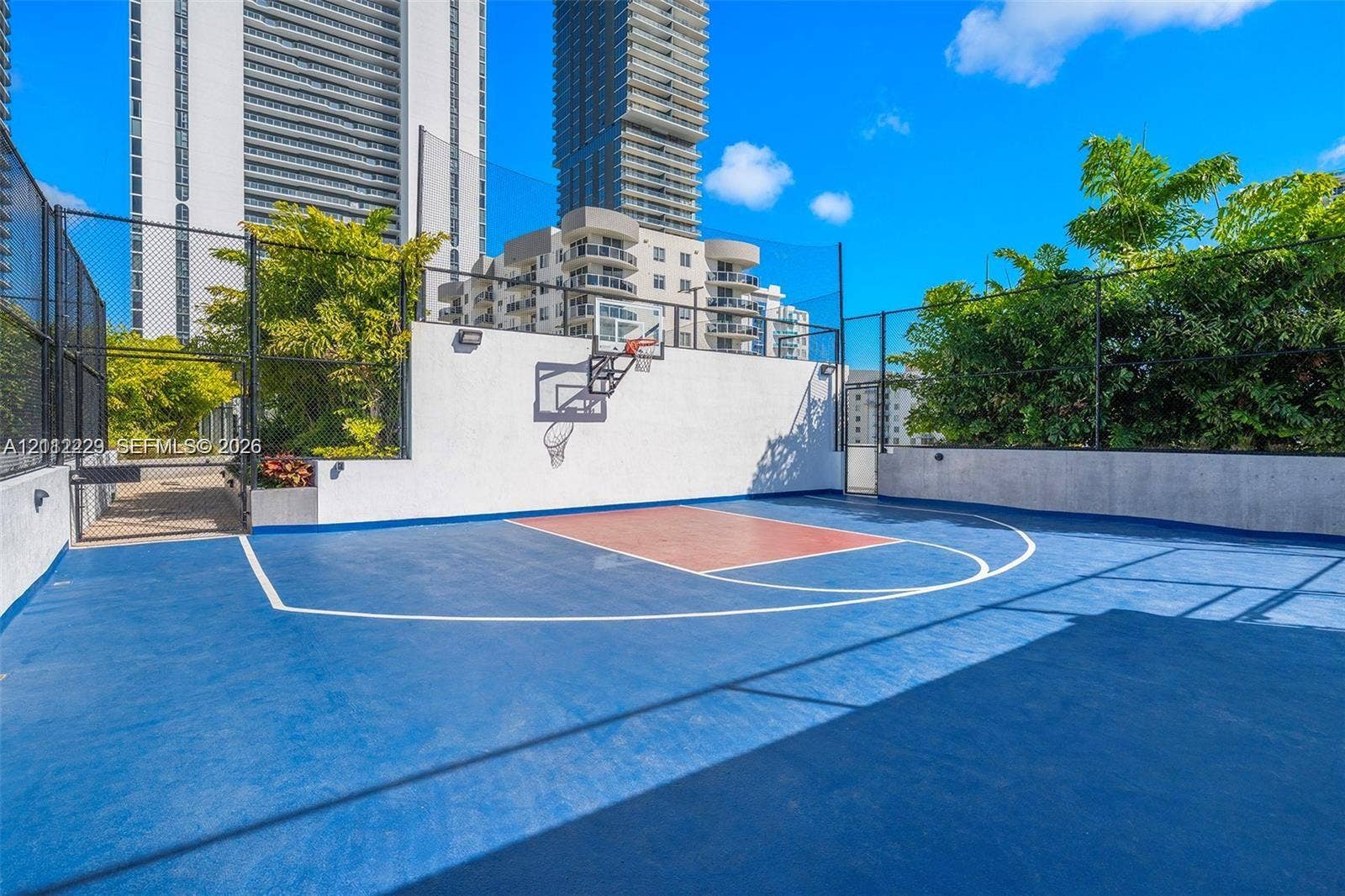 725 NE 24th Street, #706, Miami, Miami, FL 33137 Outdoor basketball court featuring a multi-tone surface, wall-mounted hoop, and high perimeter mesh fencing