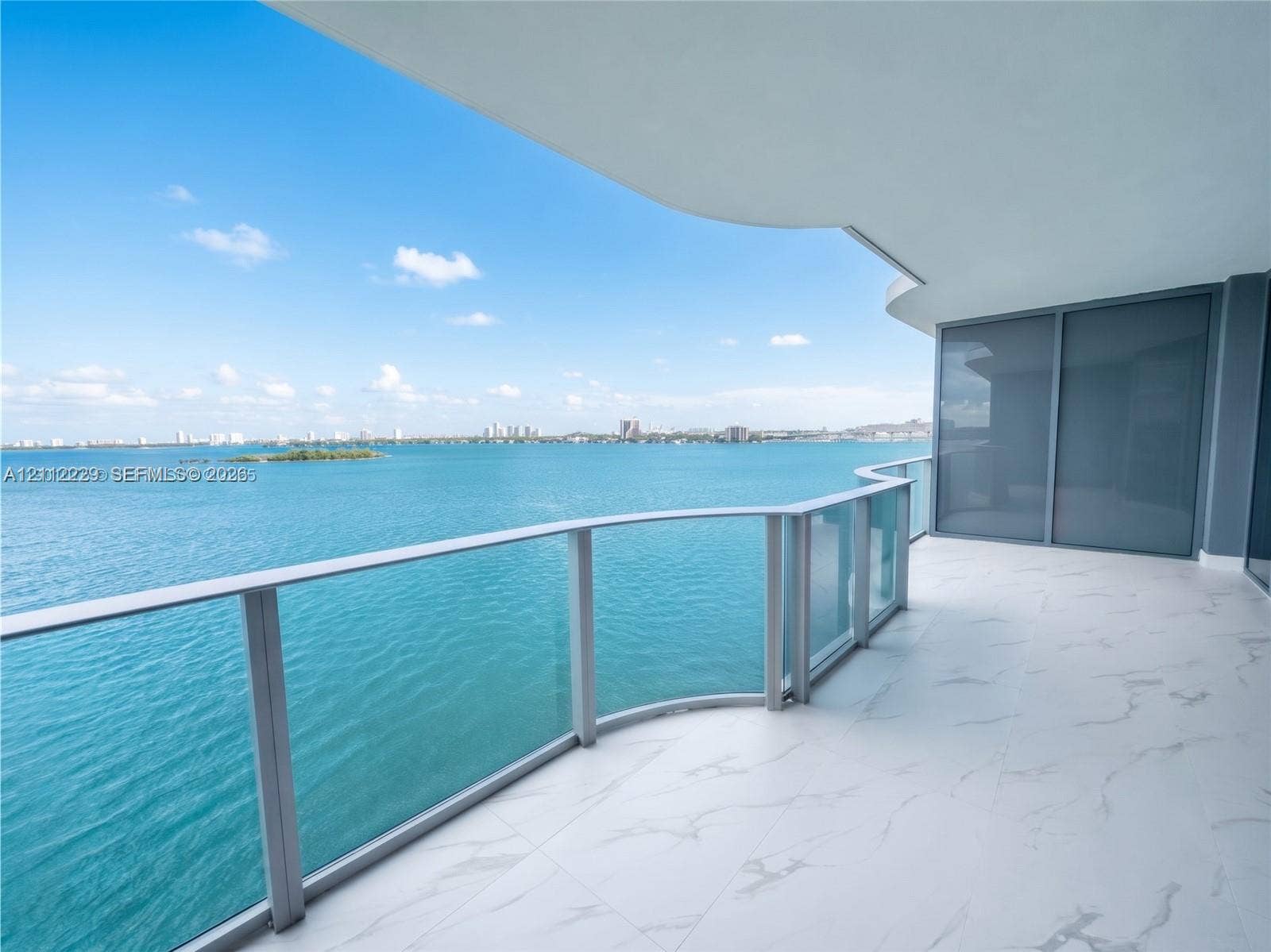 725 NE 24th Street, #706, Miami, Miami, FL 33137 Expansive covered balcony featuring large-format tile flooring and a curved glass-panel railing