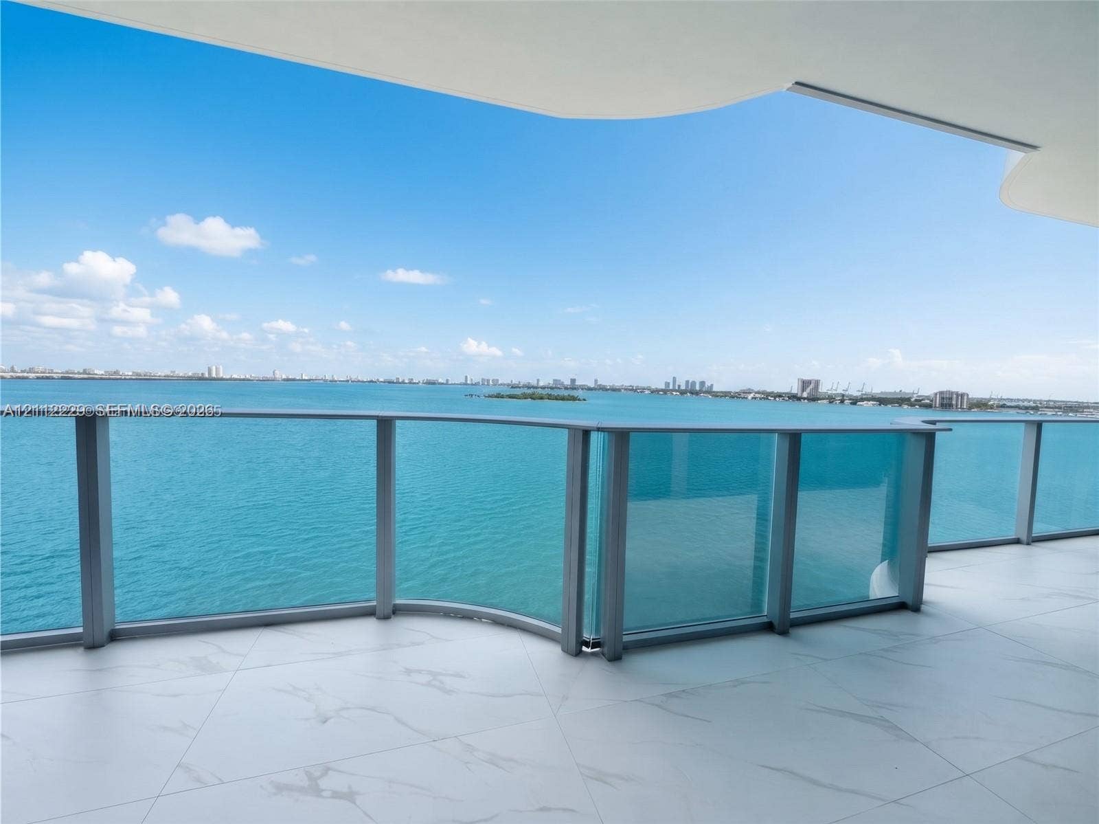 725 NE 24th Street, #706, Miami, Miami, FL 33137 Expansive covered balcony featuring white tiled flooring and a glass panel railing overlooking the water