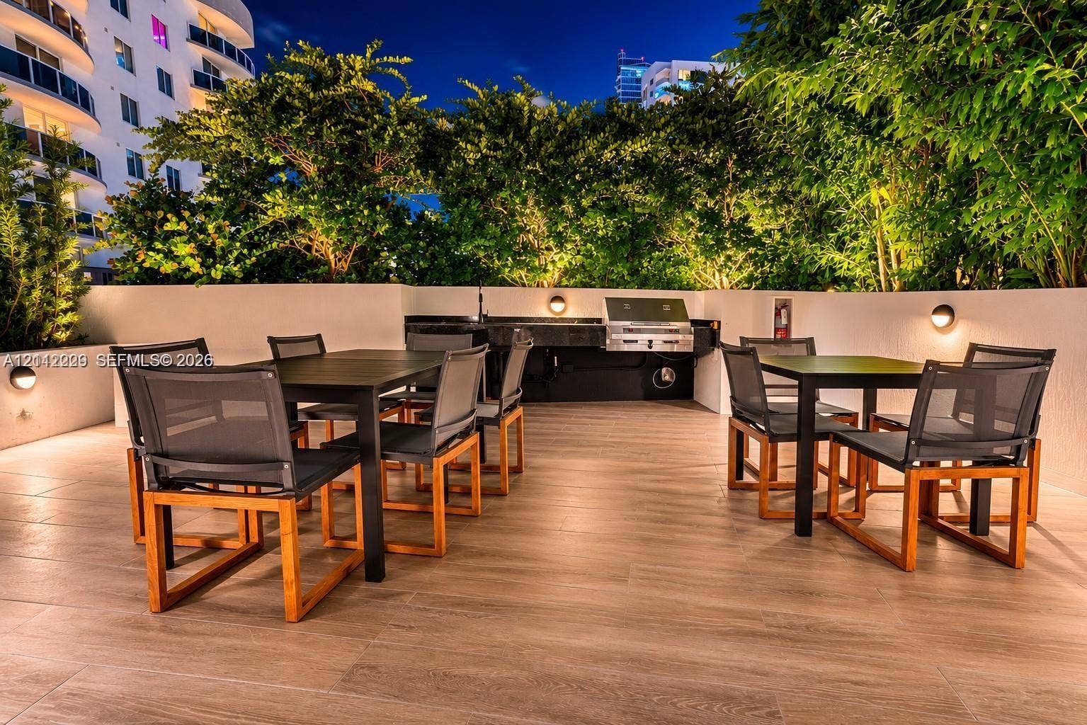 725 NE 24th Street, #706, Miami, Miami, FL 33137 Outdoor terrace featuring wood-finish tile flooring, built-in stainless steel grill, solid surface countertop, wall-mounted light fixtures, and perimeter privacy walls