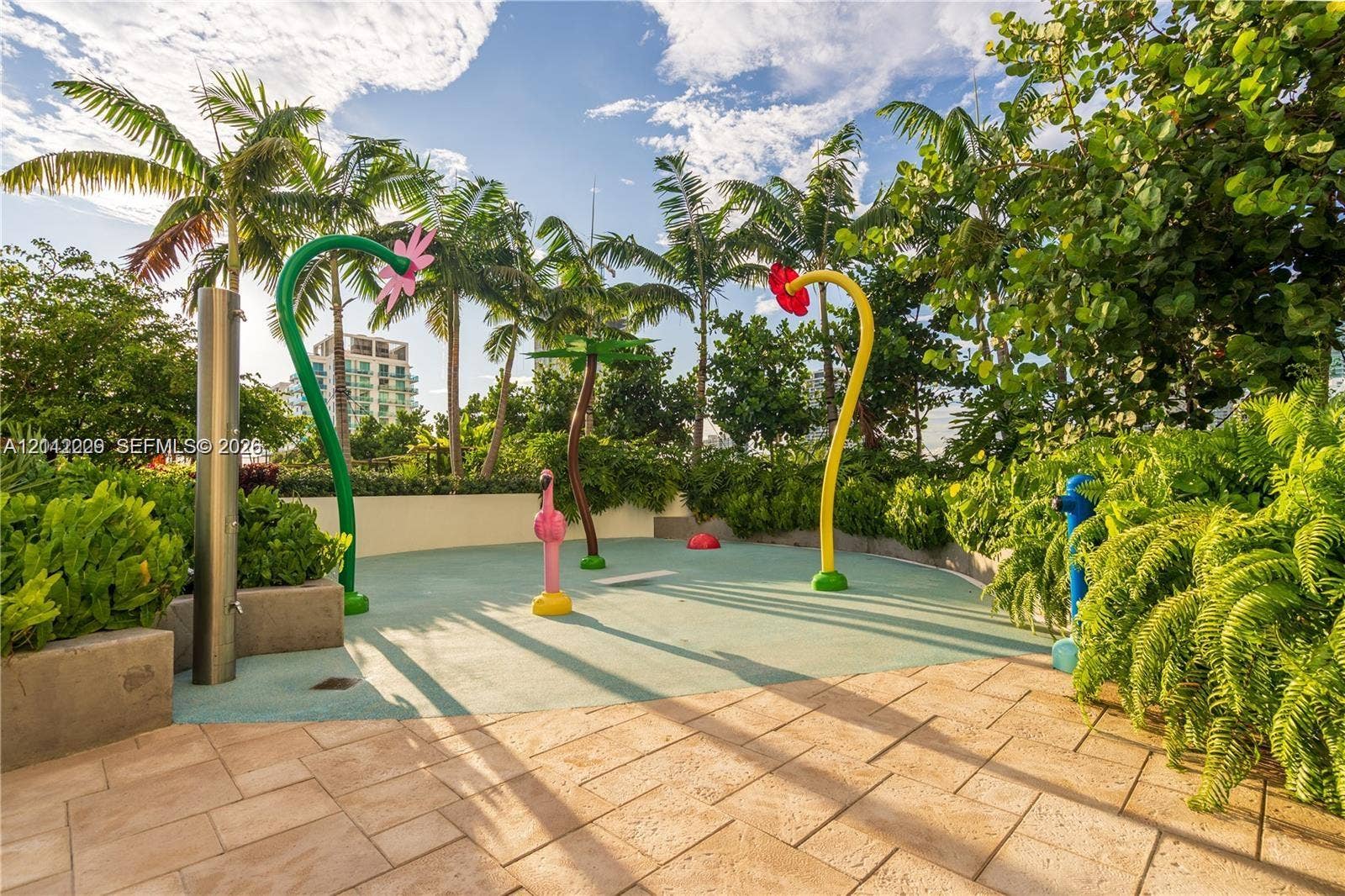 725 NE 24th Street, #706, Miami, Miami, FL 33137 Outdoor splash pad area featuring aquatic play structures, textured soft-surface flooring, stone paver decking, and perimeter landscaping with mature palms