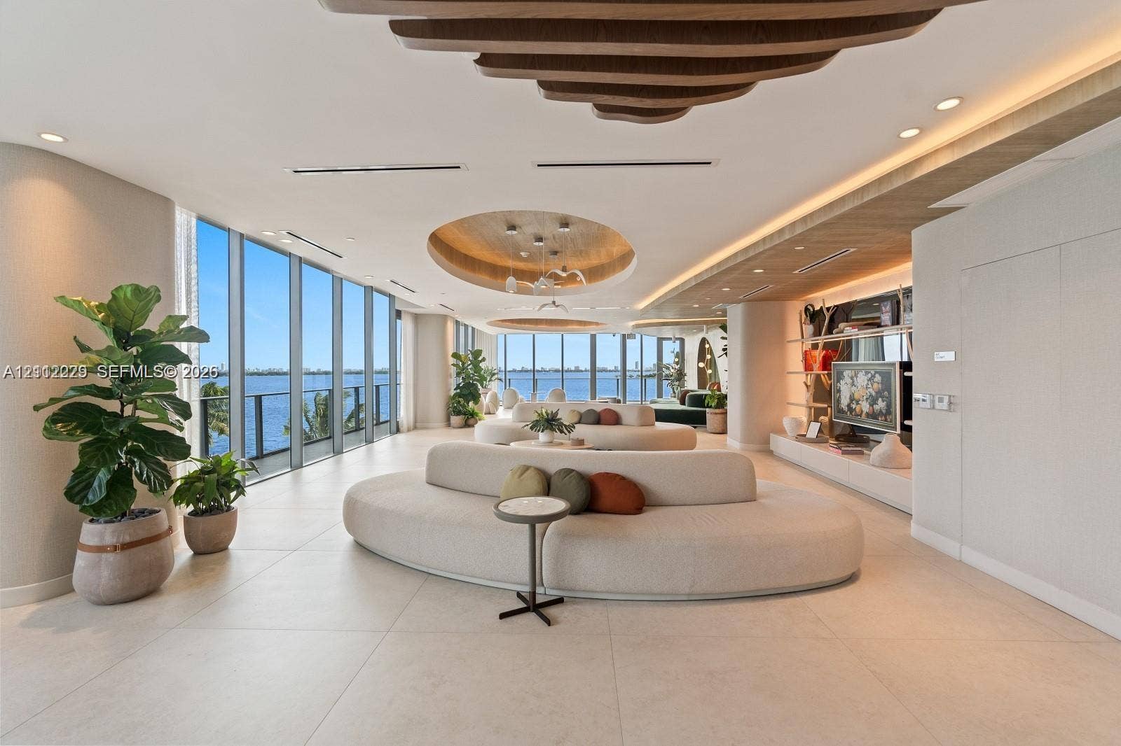 725 NE 24th Street, #706, Miami, Miami, FL 33137 Open-concept living space featuring floor-to-ceiling windows, large-format tile flooring, recessed circular ceiling treatments with integrated lighting, and custom built-in wood-finish shelving