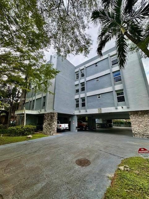 820 Salzedo Street, #305, Coral Gables, FL 33134 Multi-story residential building featuring a concrete facade, stone-clad structural pillars, and a ground-level parking area