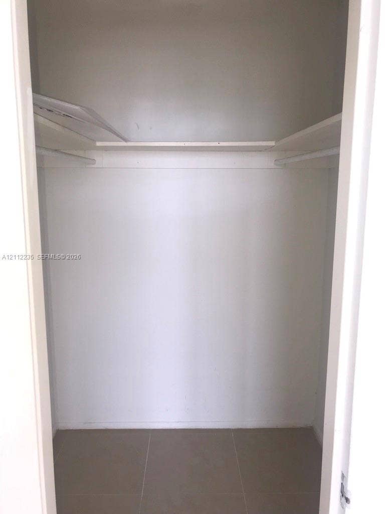 Interior closet featuring ceramic tile flooring, upper storage shelving, and integrated hanging rods