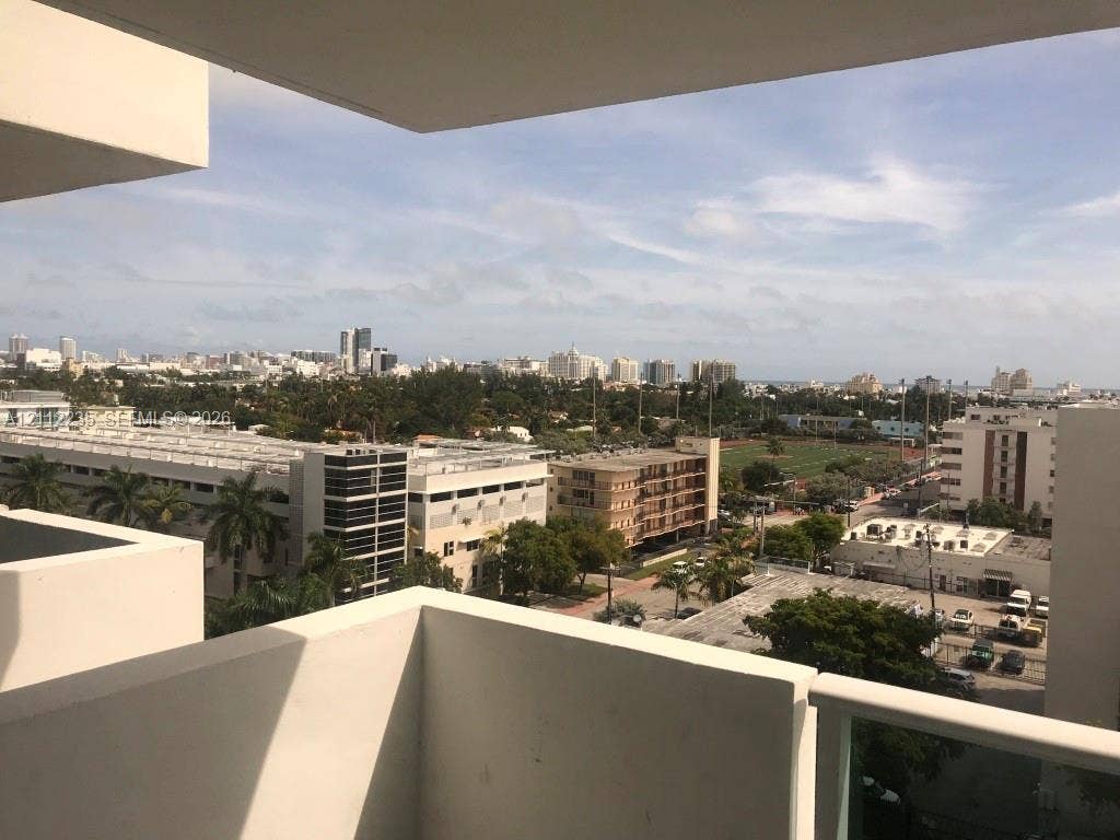 Private concrete balcony featuring a metal and glass railing, providing an elevated perspective of the surrounding cityscape