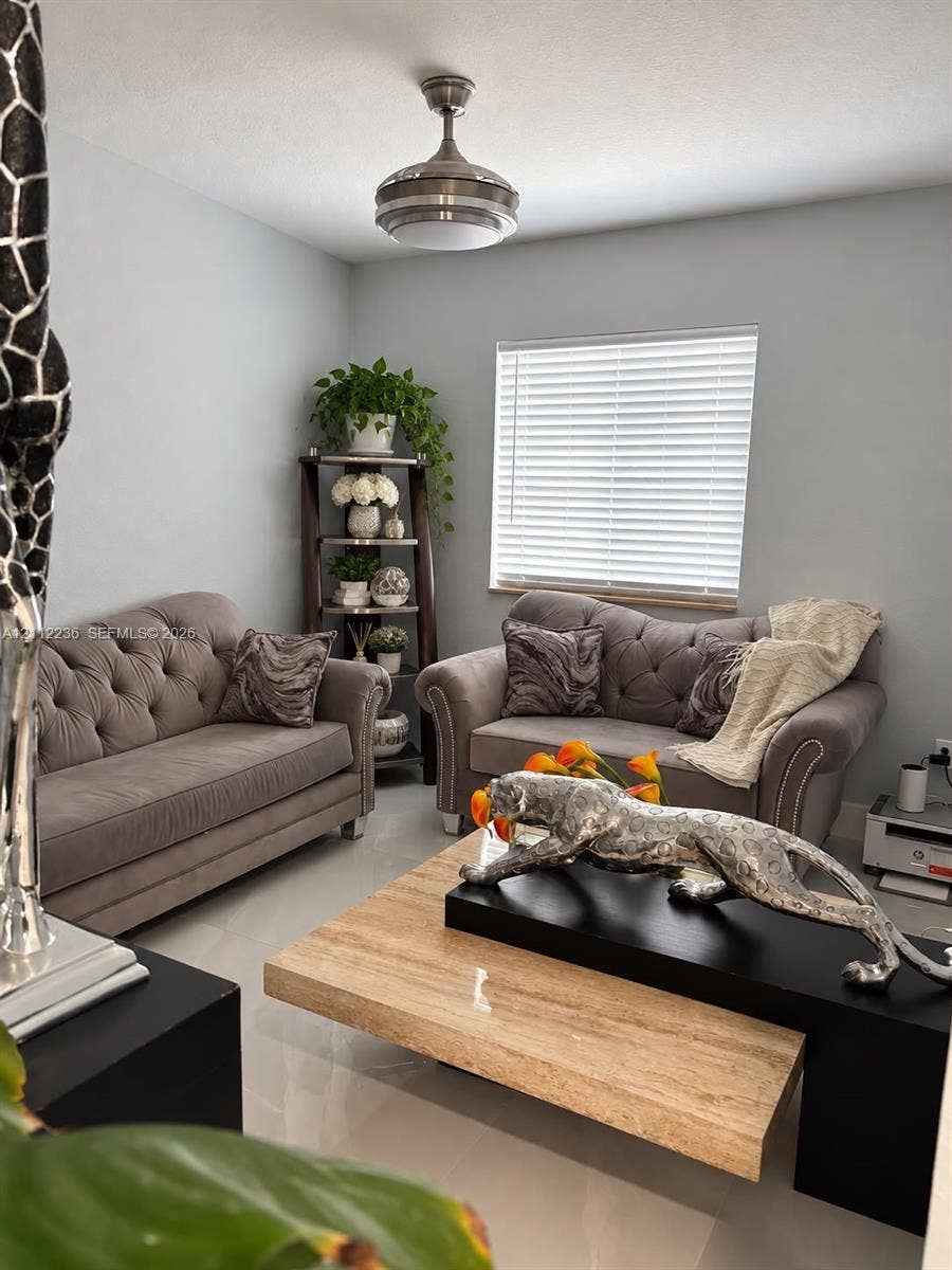 13946 SW 276th Street, #0, Homestead, FL 33032 Neutral-toned interior space featuring polished tile flooring, a horizontal blind-covered window, and a brushed nickel ceiling fan with integrated lighting