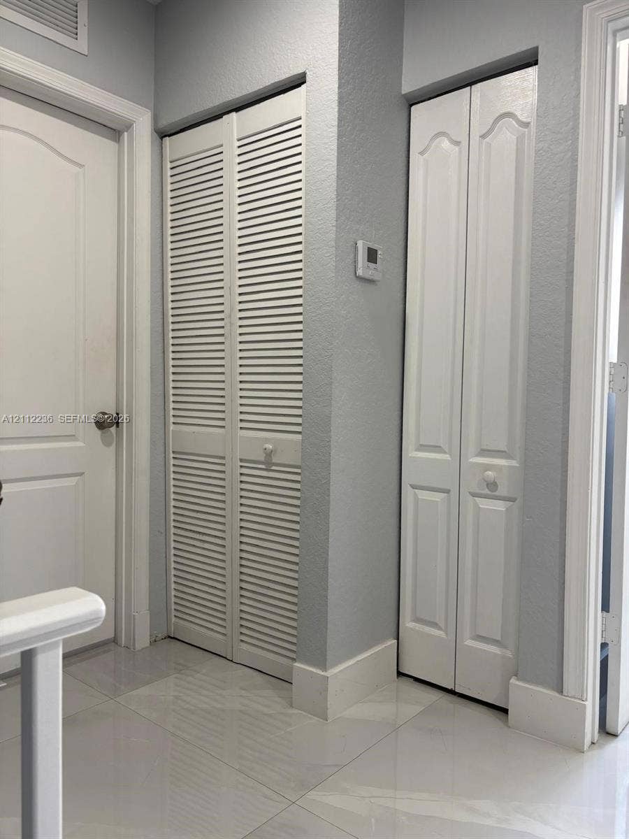 13946 SW 276th Street, #0, Homestead, FL 33032 Neutral interior featuring large-format ceramic tile flooring, white six-panel door, louvered double-door storage, and a paneled bifold door